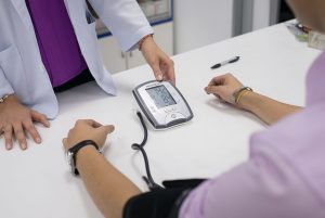 A healthcare provider helping a person measure their blood pressure using an automatic blood pressure meter.