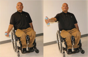 Man seated in wheelchair lifting a dumbbell to shoulder height in the scapular plane with thumb up.