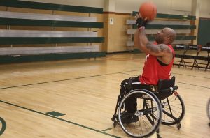 A person in a wheelchair ready to take a basketball shot.