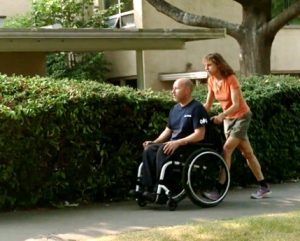 A woman pushing a man on a wheelchair