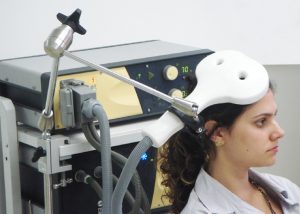 A woman with a magnetic coil placed above the head.