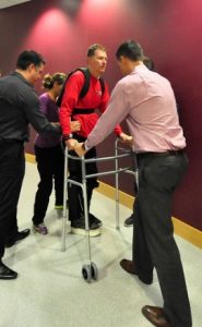 Physical therapists helping a person regain walking function with an ekoskeleton and walker