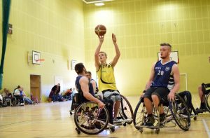 A group of men on wheelchairs playing basketball with one man about to take a shot